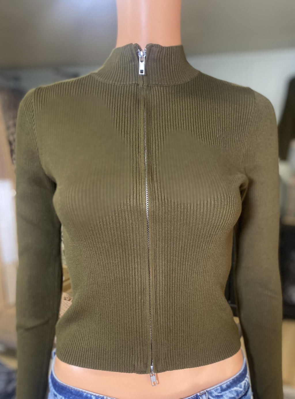 Green ribbed sweater with a 2 way zipper on a mannequin against a neutral background