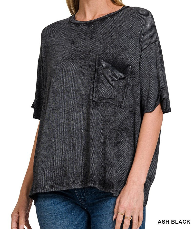 Woman wearing an oversized  acid wash black t-shirt with a pocket on a white background
